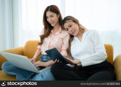 LGBT couple sitting on sofa and using laptop computer at home.