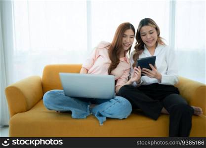 LGBT couple sitting on sofa and using laptop computer at home.