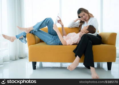 LGBT couple sitting on sofa and using laptop computer at home.