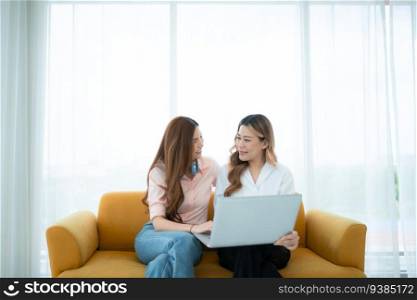 LGBT couple sitting on sofa and using laptop computer at home.