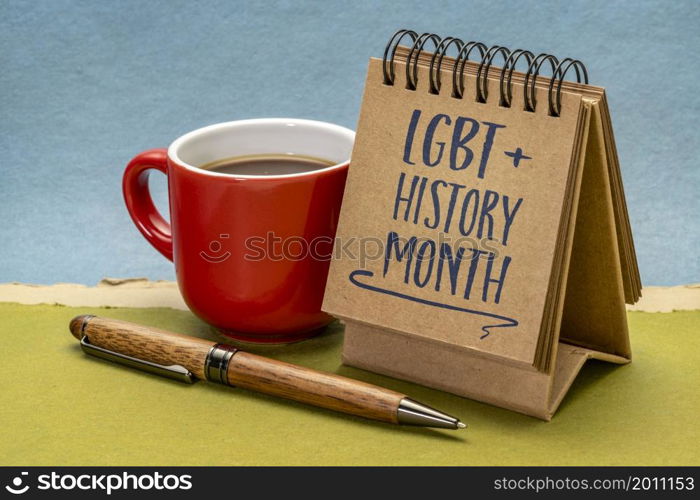 LGBT History Month - handwriting in a small desktop calendar with a cup of coffee against abstract paper landscape, reminder of cultural and heritage event
