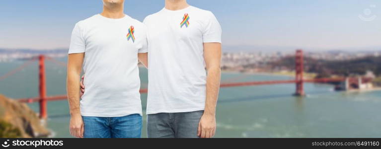 lgbt, same-sex relationships and homosexual concept - close up of male couple with gay pride rainbow awareness ribbons over golden gate bridge in san francisco bay background. close up of couple with gay pride rainbow ribbons. close up of couple with gay pride rainbow ribbons