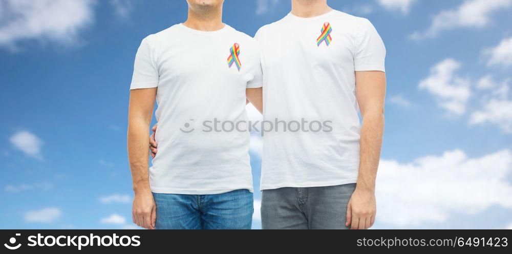 lgbt, same-sex relationships and homosexual concept - close up of male couple with gay pride rainbow awareness ribbons over blue sky and clouds background. close up of couple with gay pride rainbow ribbons. close up of couple with gay pride rainbow ribbons