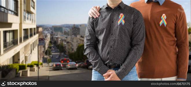 lgbt, same-sex relationships and homosexual concept - close up of male couple with gay pride rainbow awareness ribbons over san francisco city background. close up of couple with gay pride rainbow ribbons. close up of couple with gay pride rainbow ribbons