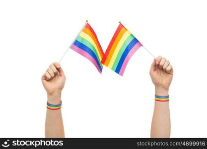 lgbt, same-sex relationships and homosexual concept - close up of male hand wearing gay pride awareness wristbands holding rainbow flags. hand with gay pride rainbow flags and wristbands. hand with gay pride rainbow flags and wristbands