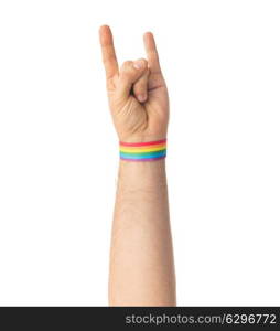 lgbt, same-sex relationships and homosexual concept - close up of male hand wearing gay pride awareness wristband showing rock or hand-horns sign. hand with gay pride rainbow wristband shows rock. hand with gay pride rainbow wristband shows rock