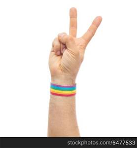 lgbt, same-sex relationships and homosexual concept - close up of male hand wearing gay pride awareness wristband showing peace sign. hand with gay pride rainbow wristband make peace. hand with gay pride rainbow wristband make peace