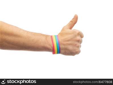lgbt, same-sex relationships and homosexual concept - close up of male hand wearing gay pride awareness wristband showing thumbs up. hand with gay pride rainbow wristband shows thumb. hand with gay pride rainbow wristband shows thumb