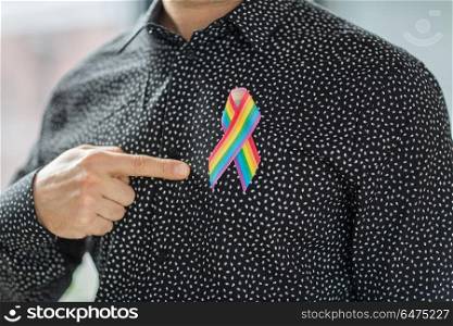 lgbt, same-sex relationships and homosexual concept - close up of man pointing finger to gay pride rainbow awareness ribbon on his chest. man with gay pride rainbow awareness ribbon. man with gay pride rainbow awareness ribbon