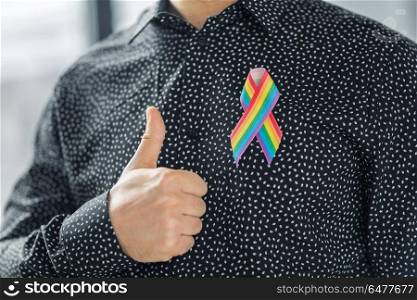lgbt, same-sex relationships and homosexual concept - close up of man with gay pride rainbow awareness ribbon on his chest showing thumbs up. man with gay pride rainbow awareness ribbon. man with gay pride rainbow awareness ribbon