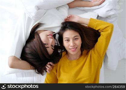 LGBT, Young cute asia lesbians lying and smiling on white bed together in the morning, couple lesbians happy moment