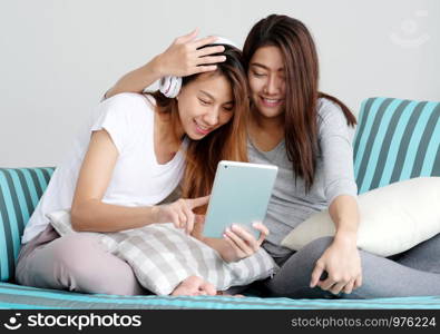 LGBT, Young cute asian lesbian couple wearing headphone and using tablet with happy moment, homosexual, lesbian couple lifestyle