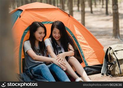 Lgbtq lesbian women couple camping or picnic together in forest, teenager female enjoy moment talking in front of their tent. Couple do adventure activity and travel on holidays vacation in summer.