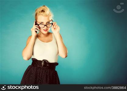 Librarian, accountant and secretary concept. Retro, pin up style. Young blonde woman in glasses. Girl holding smartphone in studio. Vintage photo.