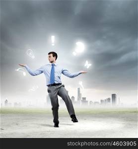 Life concepts. Young businessman juggling with conceptual symbols against city background