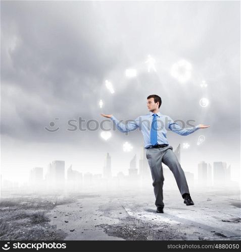 Life concepts. Young businessman juggling with conceptual symbols against city background