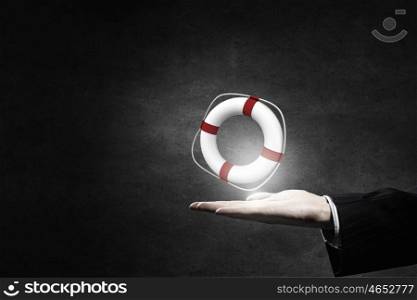 Life insurance concept. Hand of businessman on dark background holding lifebuoy
