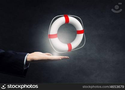 Life insurance concept. Hand of businessman on dark background holding lifebuoy