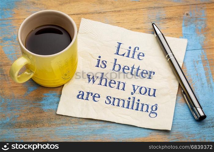 Life is better when you are smiling - inspirational handwriting on a napkin with a cup of espresso coffee