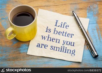 Life is better when you are smiling - inspirational handwriting on a napkin with a cup of espresso coffee