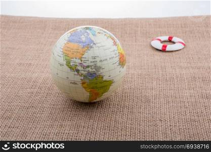Life preserver beside a globe placed on canvas background