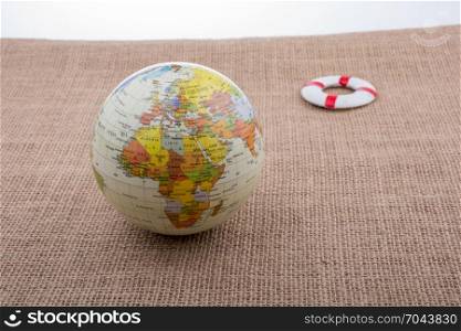 Life preserver beside a globe placed on canvas background