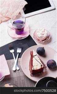 life style set at meeting in cafe.Thai blue, Butterfly pea tea served with fresh figs and panna cotta cake and fruit piece of cake on serving napkins.
