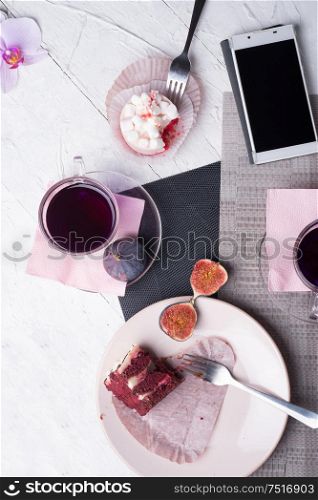 life style set at meeting in cafe.Thai blue, Butterfly pea tea served with fresh figs and panna cotta cake and fruit piece of cake on serving napkins. flat lay