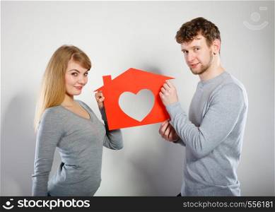 Life together. First big step in relationship. Young smiling couple in love dream plan future in their new house home. Lovely enamoured marriage full of good feelings.. Positive couple with heart house.