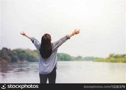 Life Unpluged. Happy Woman Standing by the River. Raising Arms to Breathing Fresh Air. Holidays Leisure and Relaxing Lifestyle