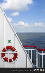 lifebuoy and part of white metal ship at sea with blue sky and clouds