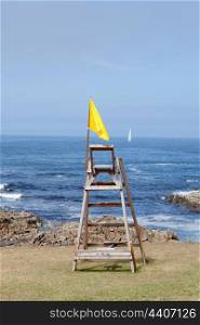 Lifeguard chair on the beach. Yellow flag, caution