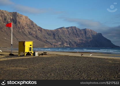 lifeguard chair red flag in spain lanzarote rock stone sky cloud beach water musk pond coastline and summer