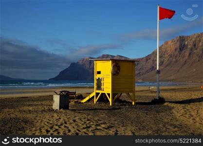 lifeguard chair red flag in spain lanzarote rock stone sky cloud beach water musk pond coastline and summer