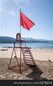 Lifeguard chair with red flag waving. No swimming concept. Beach of Galicia, Spain