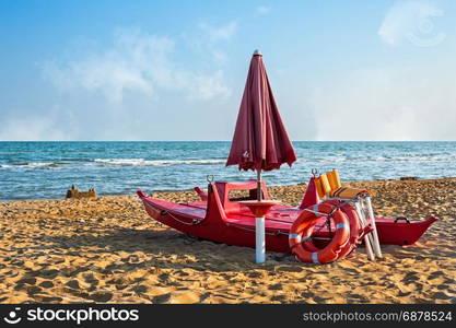 Lifeguard tools, umbrella,lifebuoy and rescue boat against beach,sea and sky