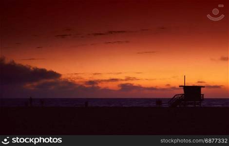Lifeguard tower at sunset in Hermosa Beach, Los Angeles, California, in the background calm water
