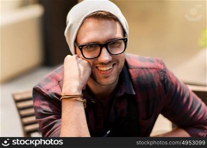 lifestyle and people concept - happy smiling man in eyeglasses and hipster hat at cafe. happy smiling man in eyeglasses and hipster hat