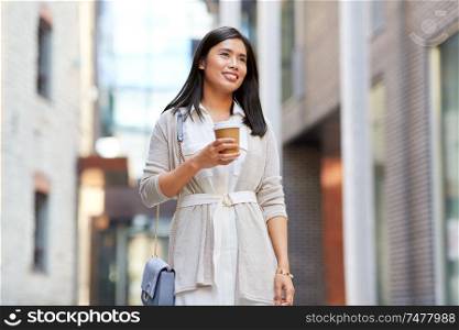 lifestyle and people concept - happy smiling young asian woman in sunglasses with takeaway coffee cup on city street. smiling woman with takeaway coffee cup in city