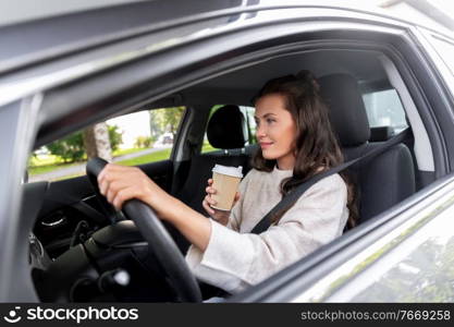 lifestyle and people concept - happy smiling young woman or female driver driving car and drinking takeaway coffee. woman or female driver with coffee driving car