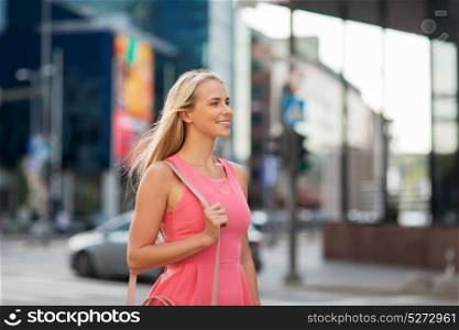 lifestyle and people concept - happy smiling young woman with bag on city street. happy smiling young woman on city street