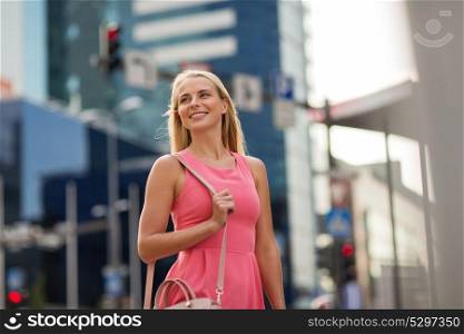 lifestyle and people concept - happy smiling young woman with bag on city street. happy smiling young woman on city street