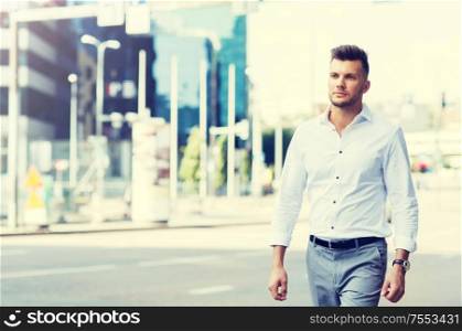lifestyle and people concept - young man walking along city street. young man walking along city street