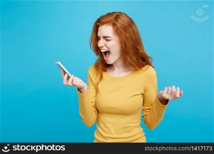 Lifestyle and Technology concept - Portrait of ginger red hair girl shouting on the phone. Isolated on Blue Pastel Background. Copy space.