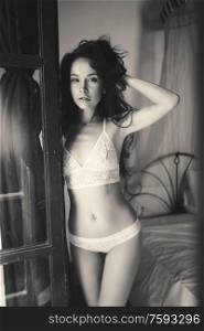 Lifestyle art photo of beautiful sensual brunette in lace lingerie by the window. Home interior. Beautiful morning