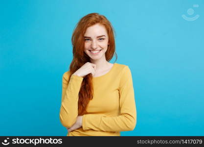 Lifestyle concept - Close up Portrait young beautiful attractive ginger red hair girl playing with her hair with shyness. Blue Pastel Background. Copy space.