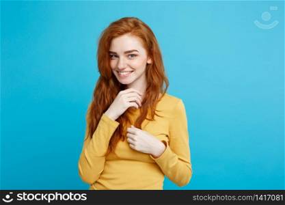 Lifestyle concept - Close up Portrait young beautiful attractive ginger red hair girl playing with her hair with shyness. Blue Pastel Background. Copy space.