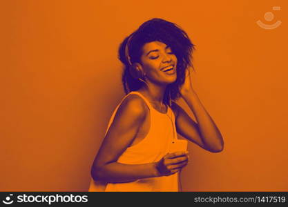 Lifestyle Concept - Portrait of beautiful African American woman joyful listening to music on mobile phone. Yellow pastel studio background. Copy Space and Duotone. Lifestyle Concept - Portrait of beautiful African American woman joyful listening to music on mobile phone. Yellow pastel studio background. Copy Space and Duotone.