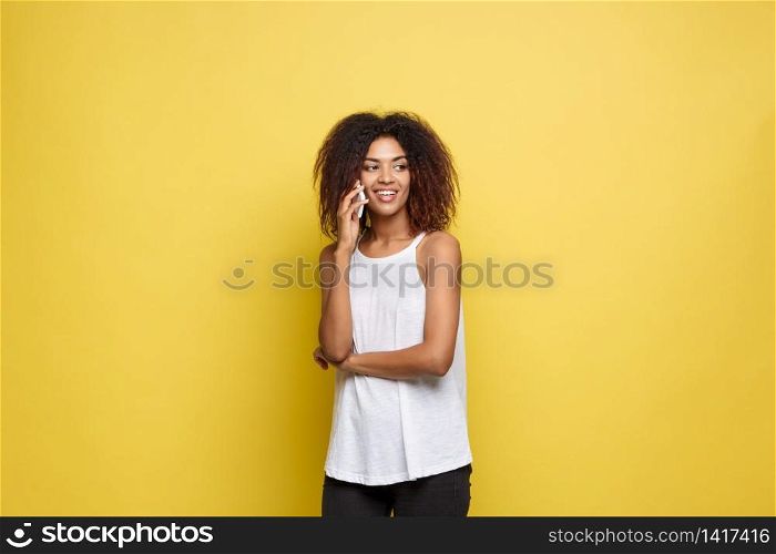 Lifestyle Concept - Portrait of beautiful African American woman joyful talking on mobile phone with friend. Yellow pastel studio background. Copy Space. Lifestyle Concept - Portrait of beautiful African American woman joyful talking on mobile phone with friend. Yellow pastel studio background. Copy Space.