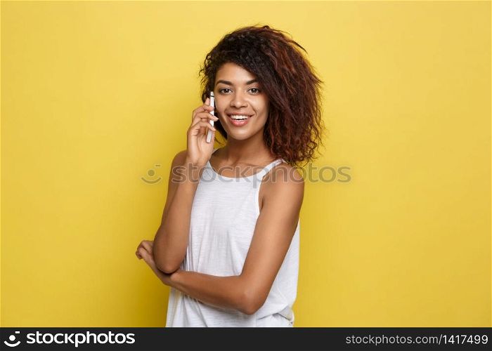 Lifestyle Concept - Portrait of beautiful African American woman joyful talking on mobile phone with friend. Yellow pastel studio background. Copy Space. Lifestyle Concept - Portrait of beautiful African American woman joyful talking on mobile phone with friend. Yellow pastel studio background. Copy Space.